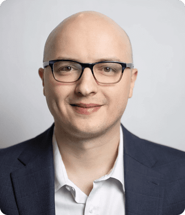 Bald man in glasses and a suit, representing Garrett Salyer, an experienced sales enablement professional.