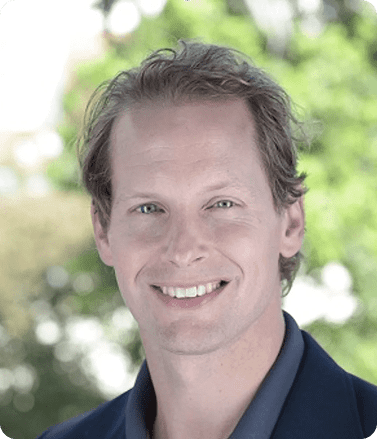 A smiling man in a blue shirt and jacket, representing Michael Green, CEO of Athena Security.