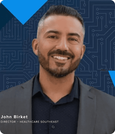 John Birket, MD, board-certified plastic surgeon and founder of his own plastic surgery practice, smiling in a professional setting.