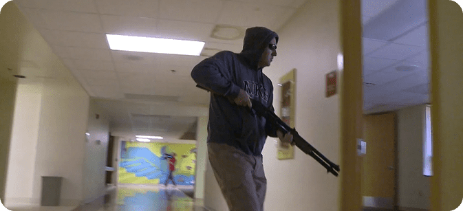 A man with a gun walks down a hallway, illustrating active shooter training for emergency preparedness.